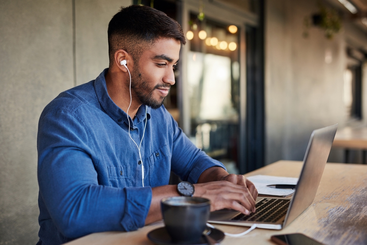 Man on laptop working or doing schoolwork wearing earphones