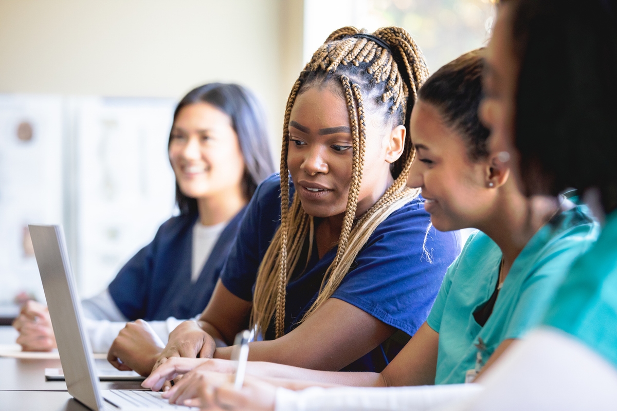 Group of female students in a lecture looking at a laptop