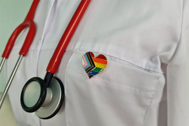 Healthcare worker wearing pride pin on lab coat